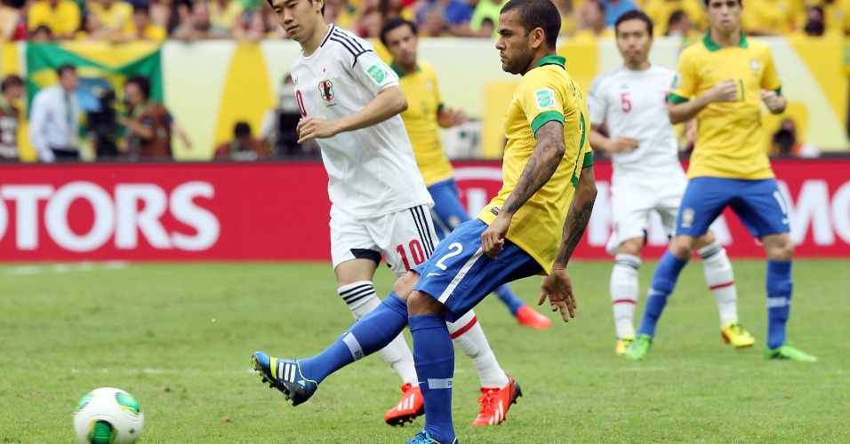 15.jun.2013 - Daniel Alves toca a bola cercado de perto por um marcador japonês na estreia da Copa das Confederações