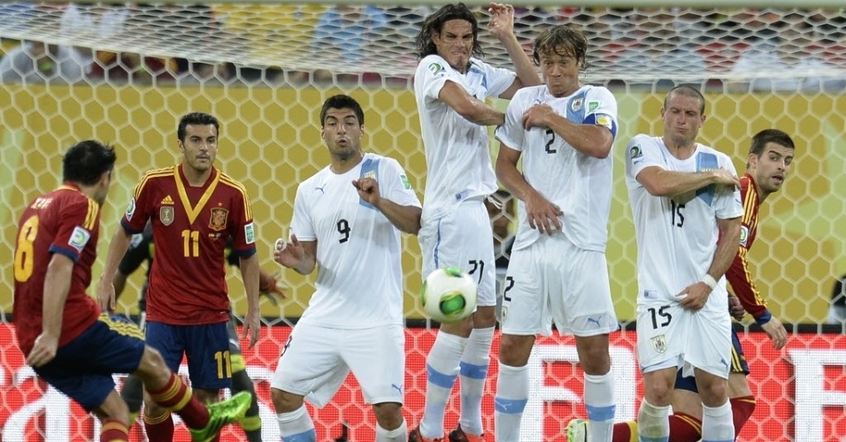 16.jun.2013 - Barreira do Uruguai salta no momento em que Xavi, da Espanha, cobra a falta