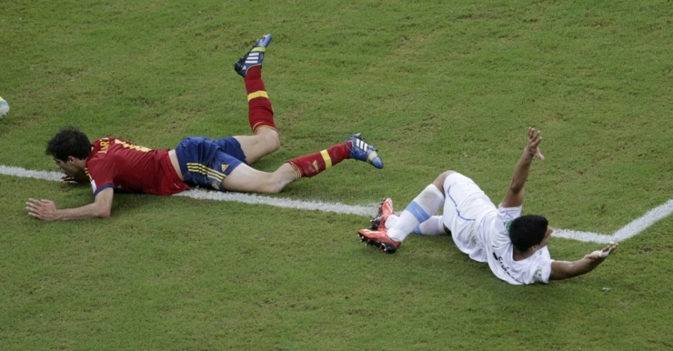 16.jun.2013 - Javi Martinez e Luis Suárez trombam e caem no chão durante o duelo Espanha e Uruguai