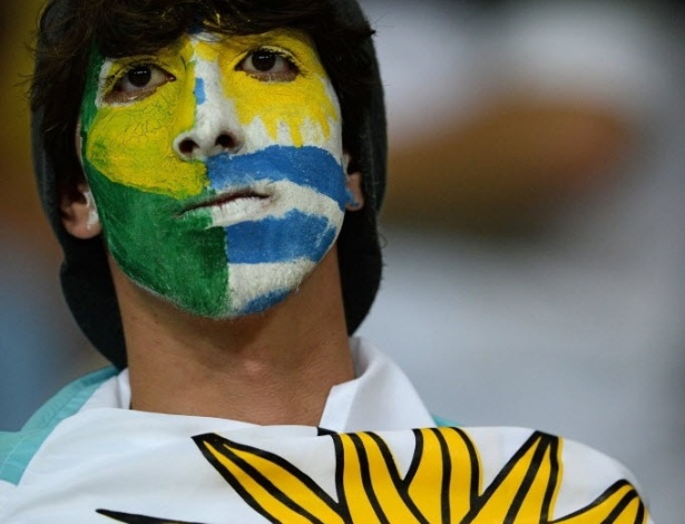 20.jun.2013 - Torcedor se enrola em bandeira do Uruguai e pinta o rosto com as cores do país e do Brasil em Salvador