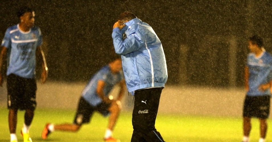 21.06.13 - Técnico Oscar Tabárez, do Uruguai, se protege da chuva durante treino da seleção