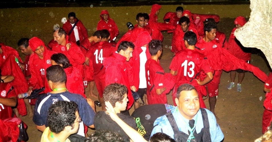 21.jun.2013 Jogadores do Taiti tenta se proteger do forte temporal na Praia de Boa Viagem, no Recife, após o treino