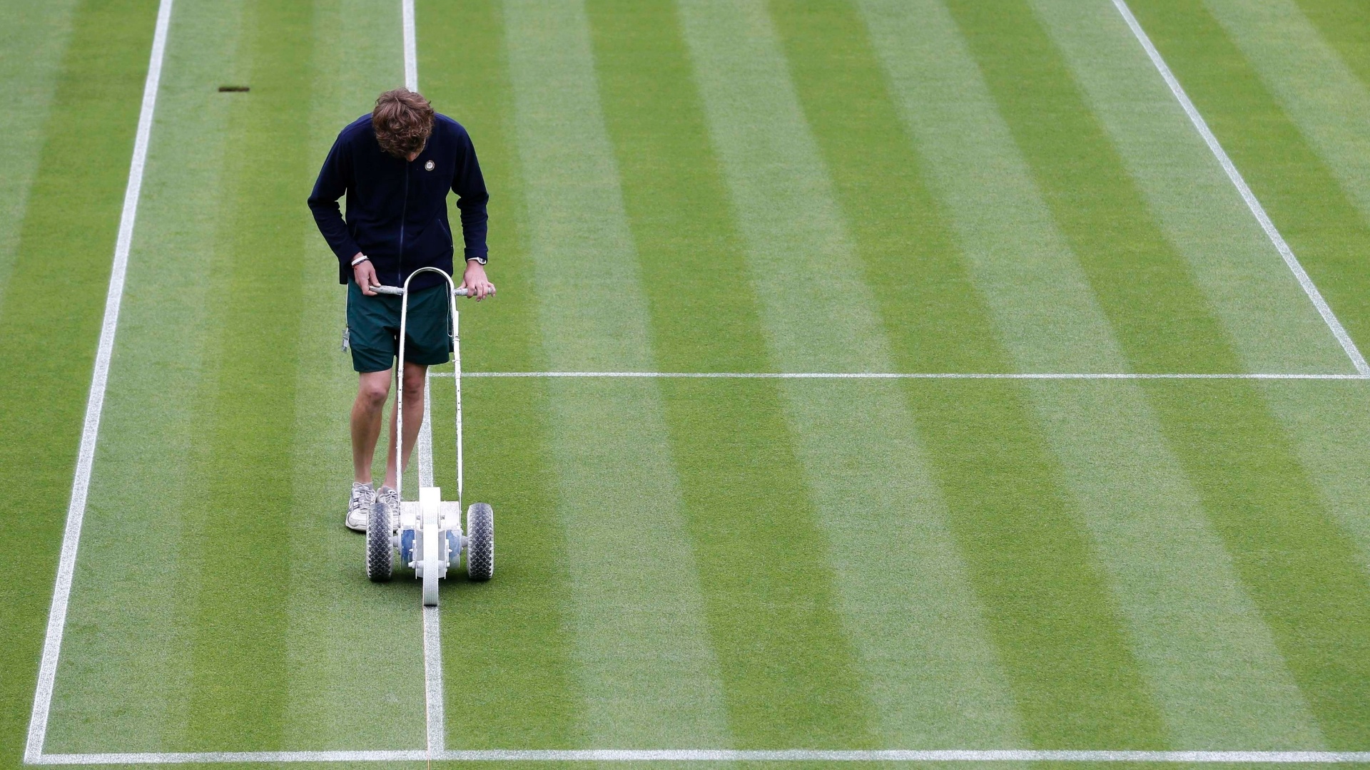 24.jun.2013 - Funcionário faz últimas marcações na quadra antes do início das disputas em Wimbledon - REUTERS/Eddie Keogh