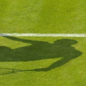 24.jun.2013 - Sombra de Jio-Wilfried Tsonga aparece na grama de Wimbledon enquanto o francês se prepara para sacar - AFP PHOTO / GLYN KIRK