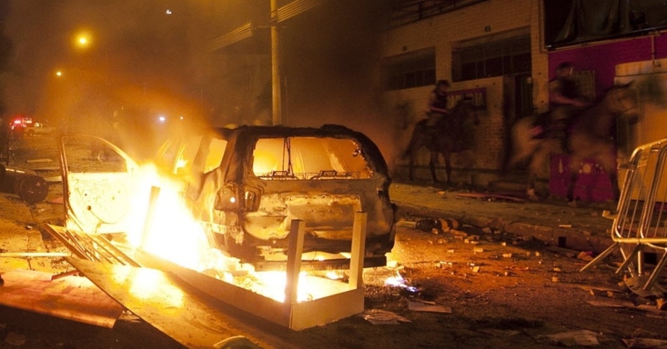 26.jun.2013 - Cavalaria passa por carro incendiado em confronto entre manifestantes e polícia próximo ao Mineirão