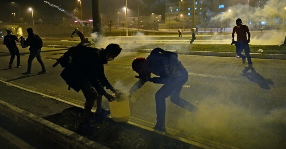 26.jun.2013 - Manifestantes tentam se proteger de bombas de efeito moral lançadas pela polícia me confronto próximo ao Mineirão