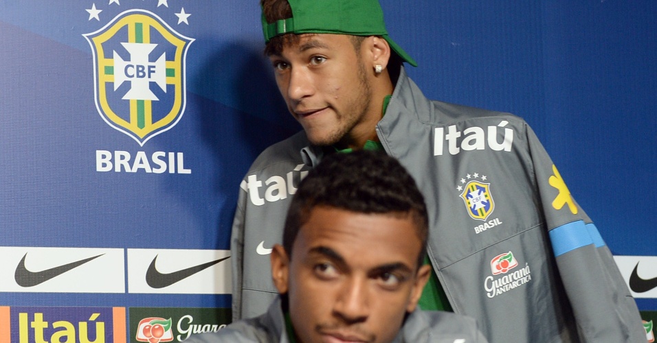 28.jun.2013 - Neymar chega para entrevista coletiva da seleção, enquanto Luiz Gustavo fala