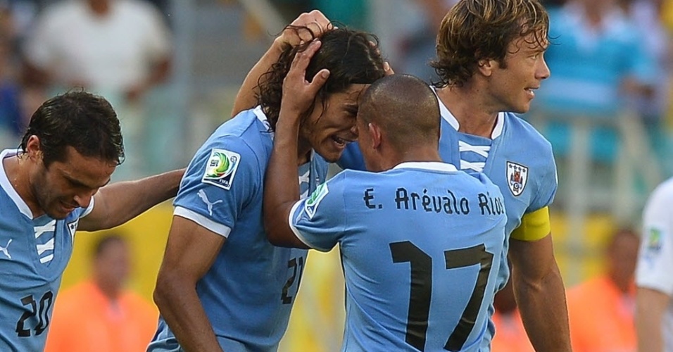 30.jun.2013 - Cavani é abraçado por companheiros após anotar gol de falta, novo empate do Uruguai contra a Itália
