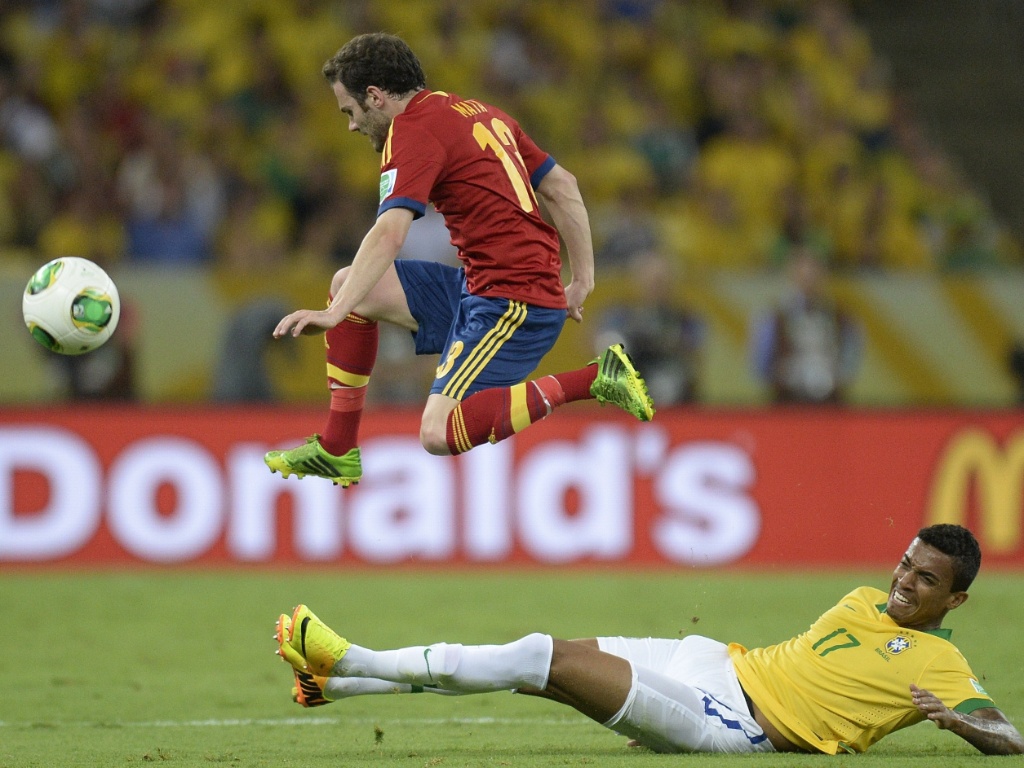 30.jun.2013 - Espanhol Juan Mata salta para fugir de carrinho de Luiz Gustavo durante final da Copa das Confederações