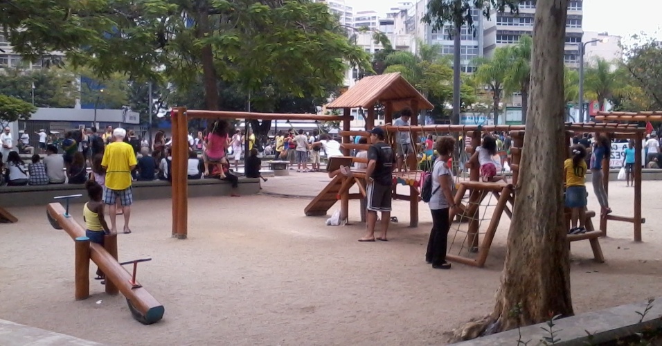 Crianças brincam no parquinho da praça em meio à manifestação