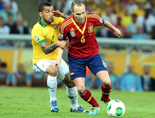 Iniesta (dir.), meia da Espanha, controla a bola com a marcação do brasileiro Daniel Alves