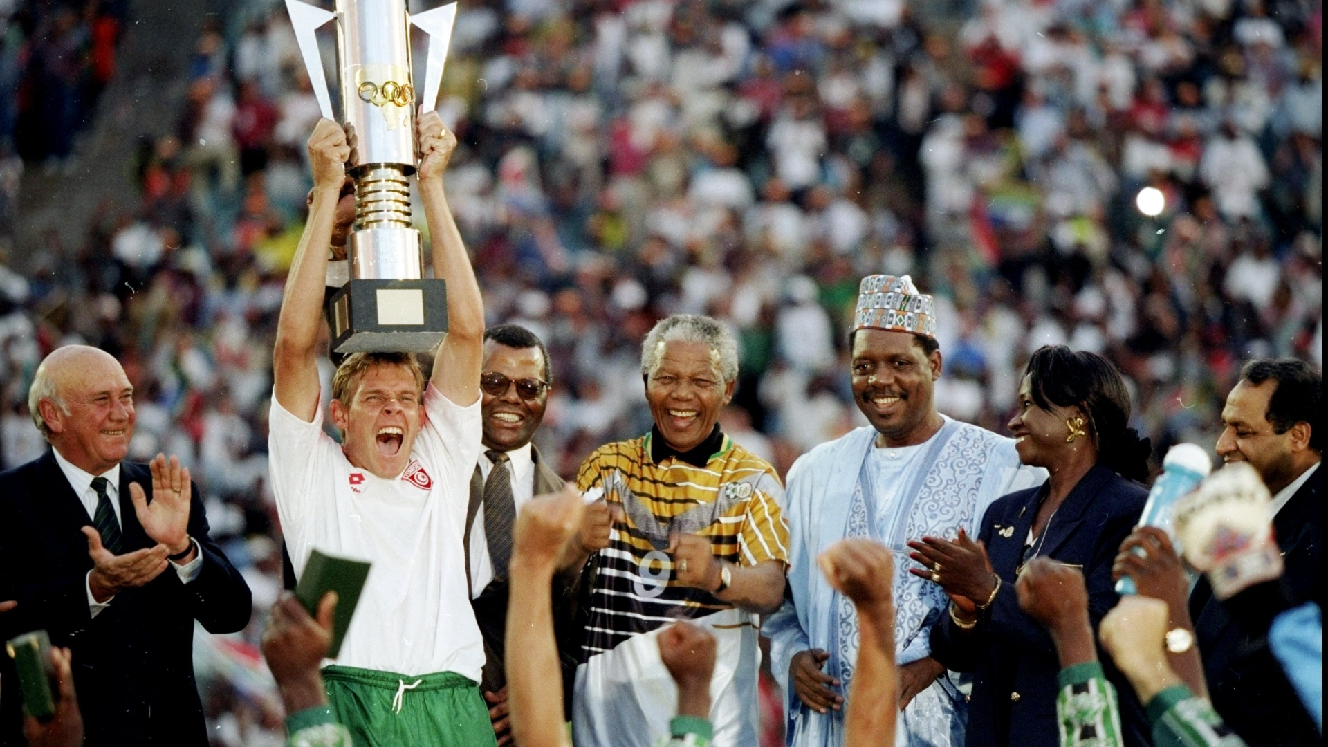 09.fev.1996 - Ao lado do presidente Nelson Mandela (e), Neil Touey (e) ergue a taça de campeão da Copa Africana de Nações conquistada em casa pela África do Sul após final contra a Tunísia. Os anfitriões venceram o jogo por 2 a 0 - Mark Thompson /Allsport