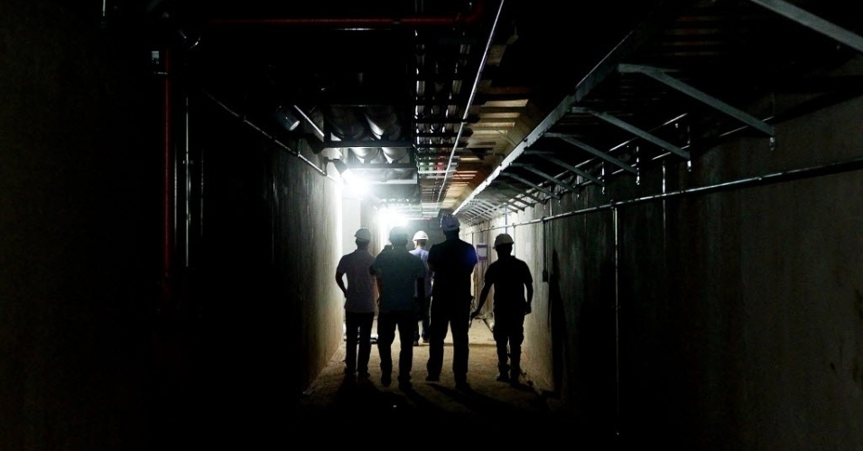 Funcionários conversam no corredor interno do Itaquerão, que mostra o encanamento e a estrutura do local