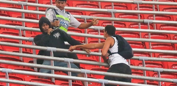 Policial tenta evitar briga entre torcedores na partida entre Corinthians e Vasco, no estádio Mané Garrincha - Sergio Lima/Folhapress