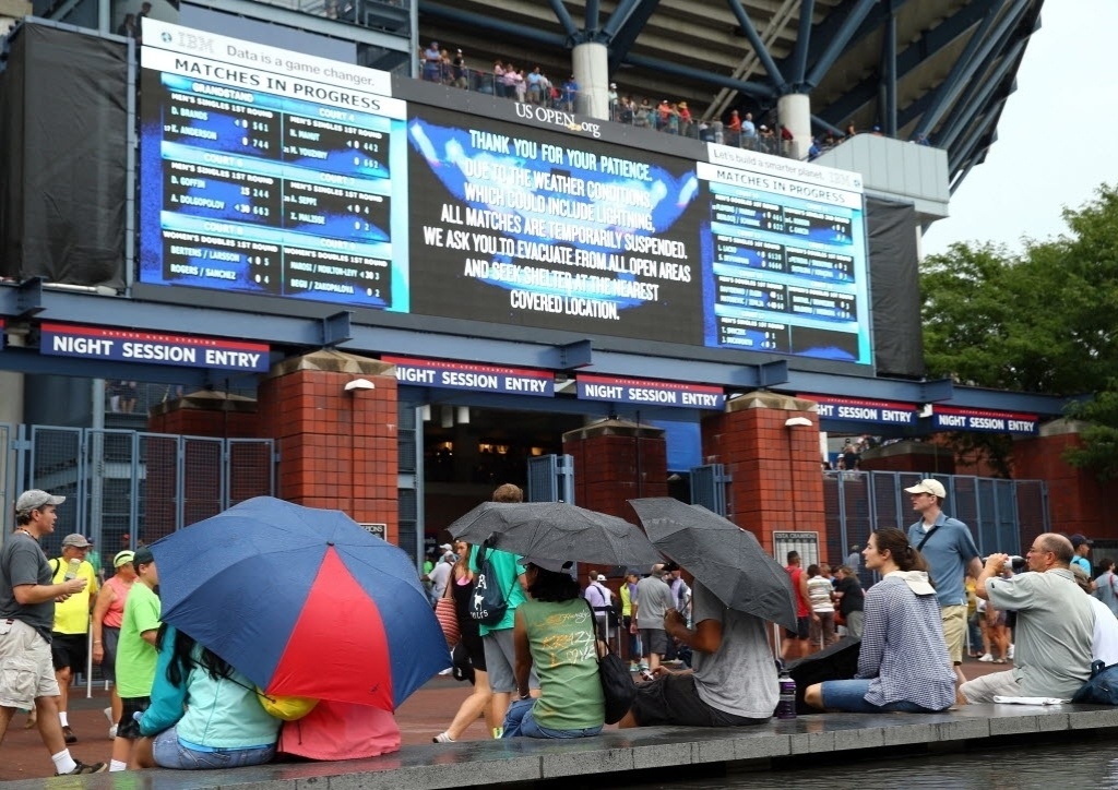 28.ago.2013 - Espectadores se protegem da chuva durante o terceiro dia do Aberto dos EUA - Elsa/Getty Images/AFP