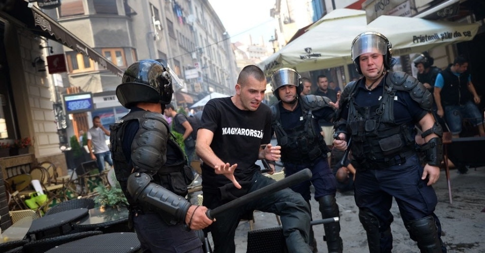 6.set.2013 - Policiais romenos cercam torcedor húngaro em conflito antes do jogo entre os países pelas Eliminatórias