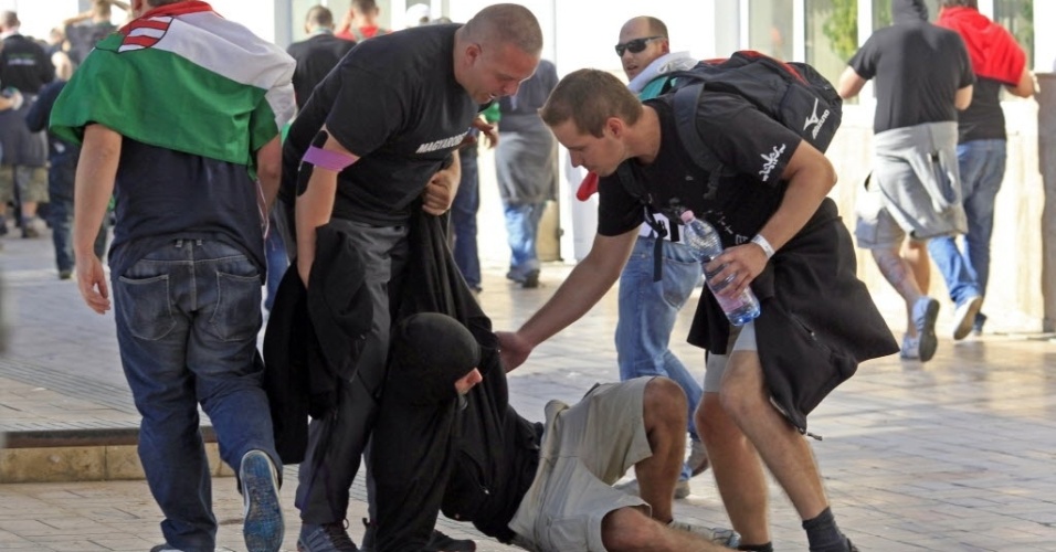 6.set.2013 - Torcedores húngaros ajudam homem caído após conflito com policiais romenos - os países se enfrentam pelas Eliminatórias da Copa-2014