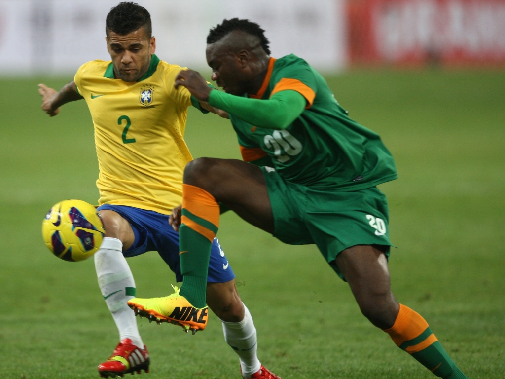 15.out.2013 - Daniel Alves marca jogador da Zâmbia durante o amistoso em Pequim