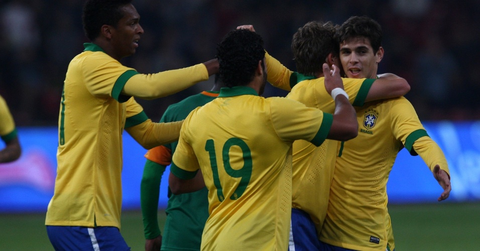 15.out.2013 - Oscar é abraçado por companheiros após abrir o placar para o Brasil contra a Zâmbia