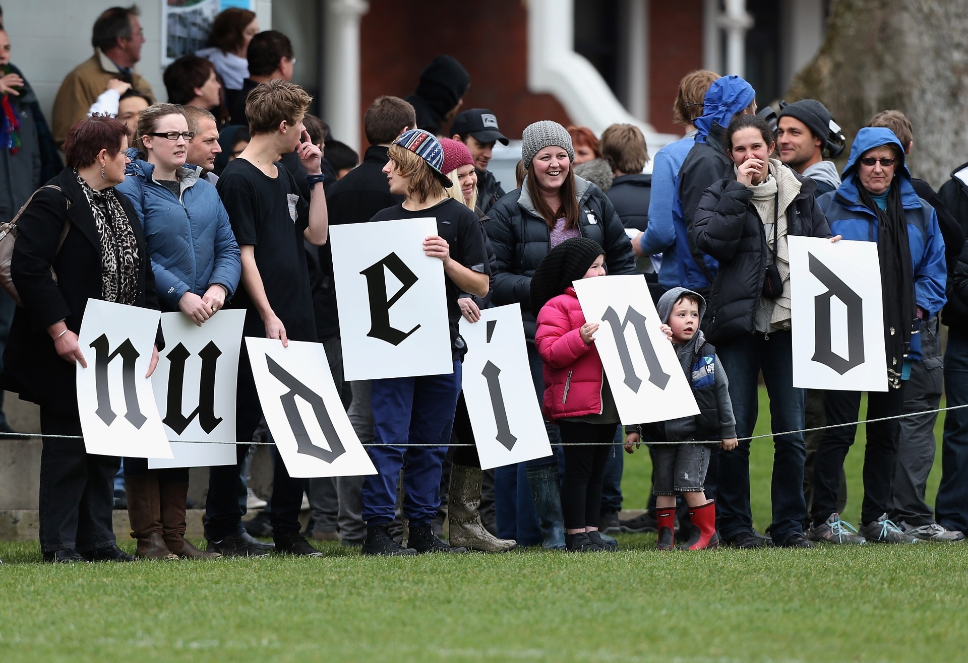 Multidão, incluindo crianças, se reúne no campo para acompanhar o jogo - Sandra Mu/Getty Images