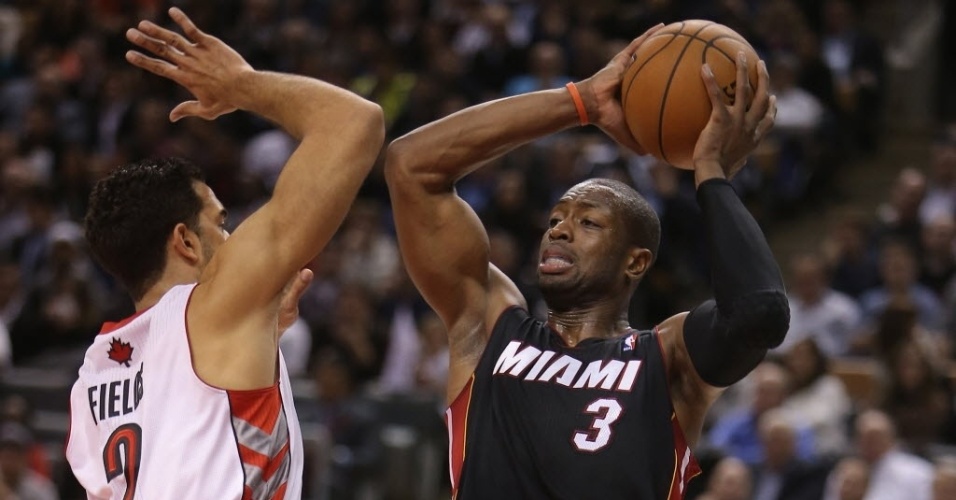 05.nov.2013 - Dwyane Wade (dir.) disputa bola com Landry Fields durante partida da NBA entre Miami Heat e Toronto Raptors