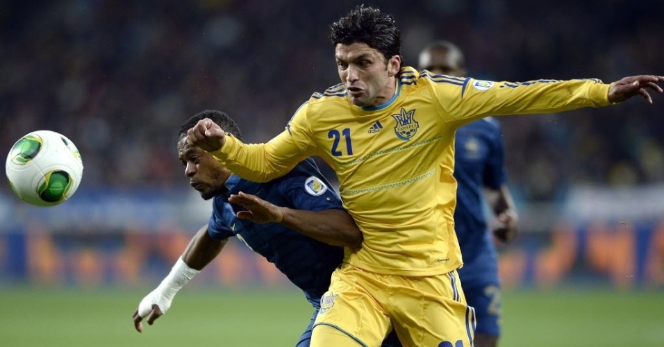 15.nov.2013 - Edmar (dir.), brasileiro naturalizado ucraniano, briga pela bola com o francês Evra em partida da repescagem para a Copa do Mundo