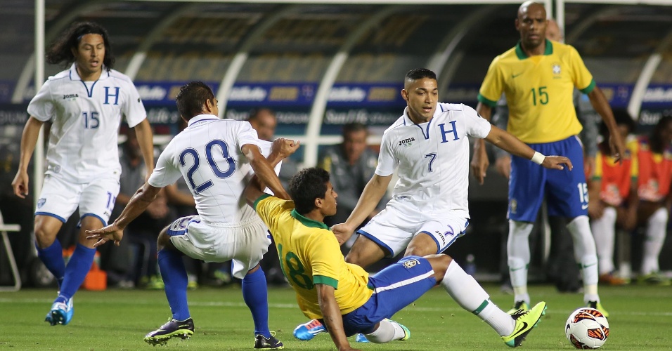 16.nov.2013 - Marcado por dois hondurenhos, Paulinho cai no chão em disputa de bola durante jogo da seleção brasileira em Miami