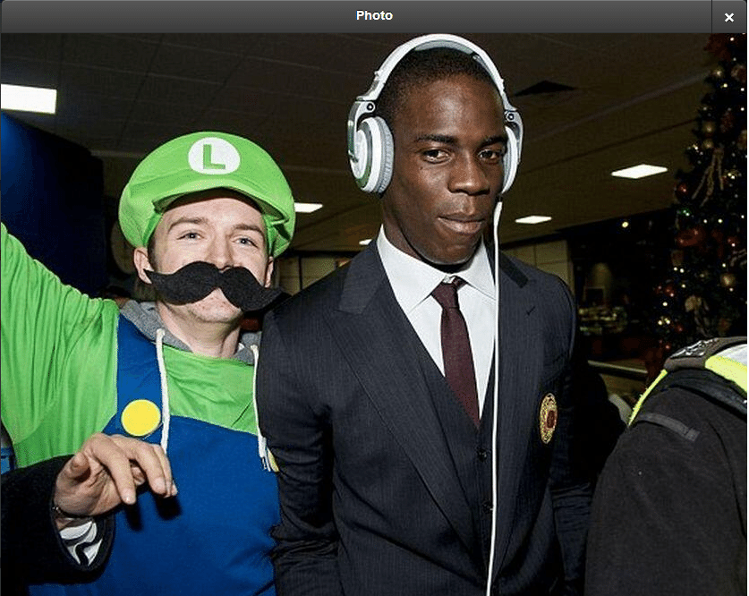25.nov.2013 - Mario Balotelli é recebido em aeroporto na Escócia por torcedor fantasiado de Luigi