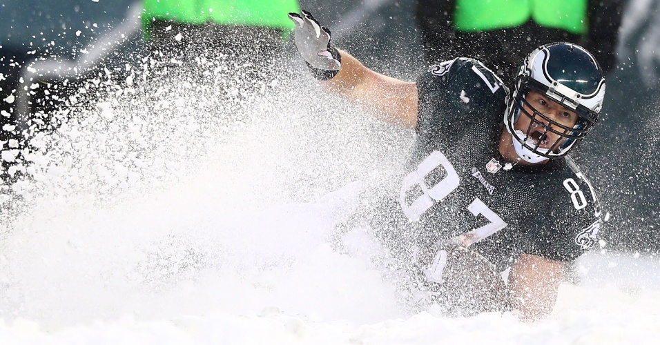 8.dez.2013 - Brent Celek, do Philadelphia Eagles, desliza na neve para conseguir o primeiro ponto da equipe contra o Detroit Lions