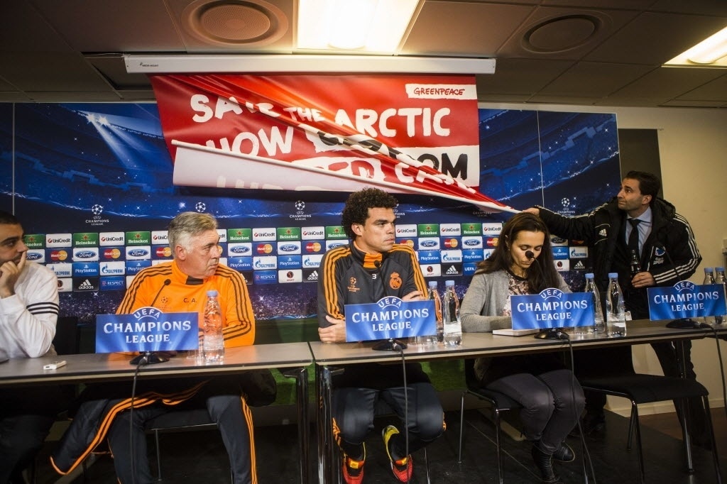09.dez.2013 - Funcionário retira faixa de protesto contra empresa petrolífera atrás de técnico e jogadores durante coletiva de imprensa do Real Madrid - AFP PHOTO / Scanpix Denmark /NIKOLAI LINARES /