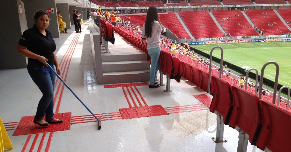 Funcionários da manutenção tentam conter com rodos água da chuva que vaza de emenda na cobertura do estádio Mané Garrincha, neste domindo (22), durante jogo de futebol feminino entre as seleções do Canadá e Escócia
