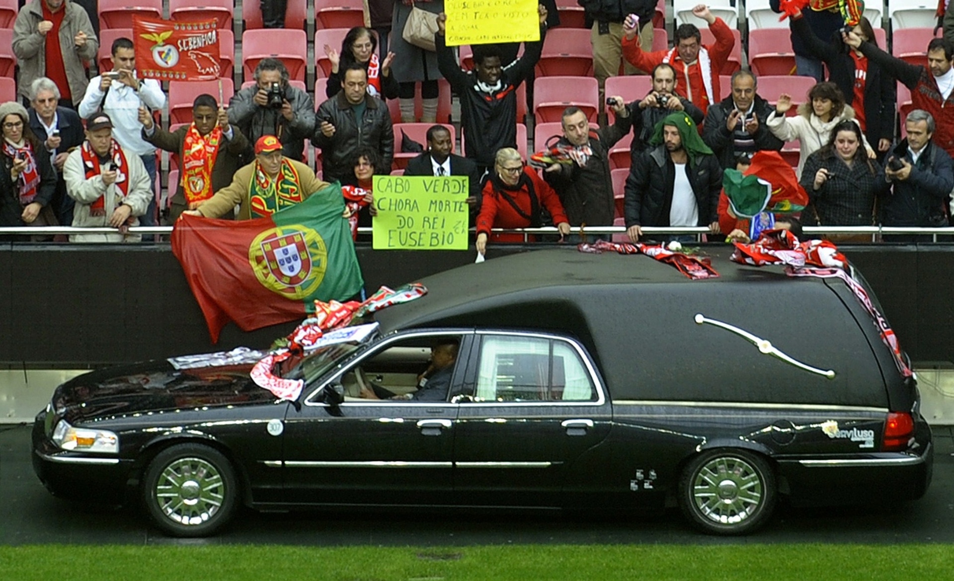6.jan.2014 - Torcedores exibem cartazes e faixas enquanto carro com o corpo de Eusébio passa próximo as arquibancadas dos Estádio da Luz, em Lisboa - AFP PHOTO/ MIGUEL RIOPA