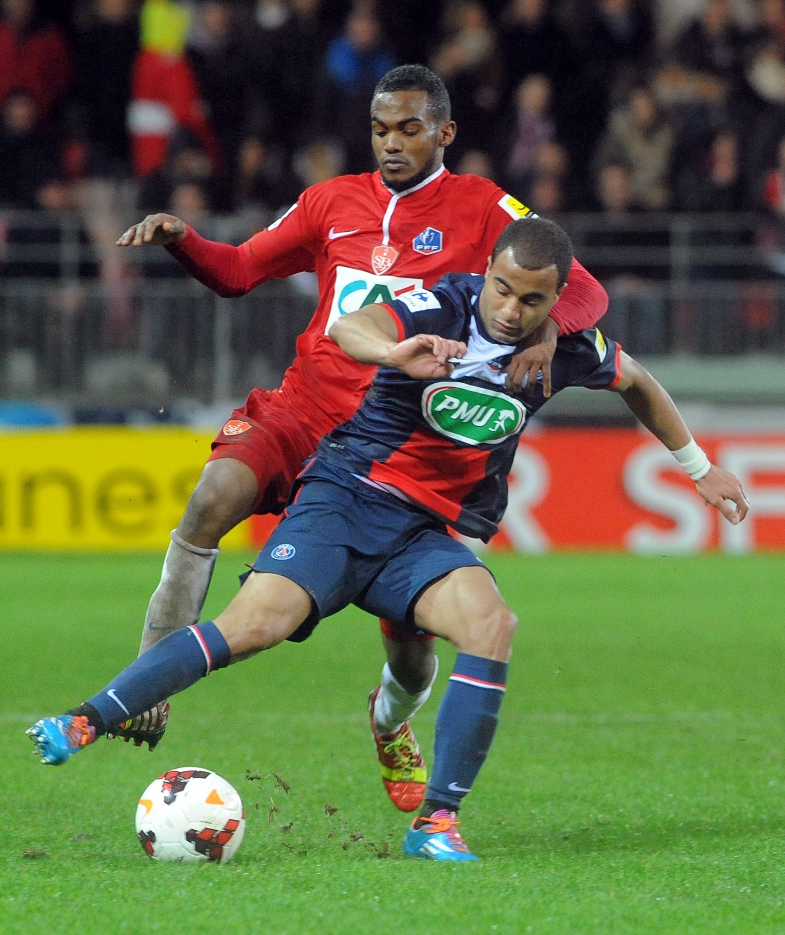 08.jan.2014 - Meia Lucas, do PSG, tenta escapar da marcação de meia do Brest durante jogo da Copa da França - AFP PHOTO/FRED TANNEAU