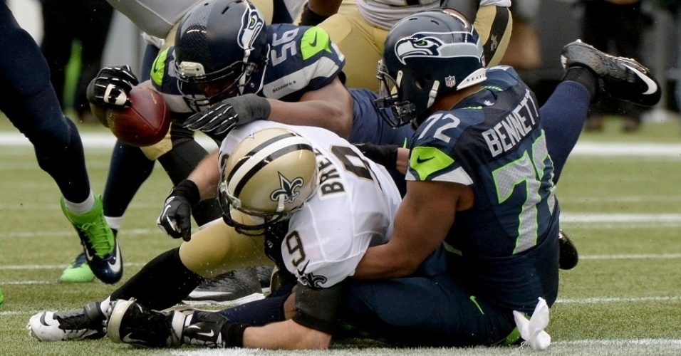 11.jan.2014 - Quarterback Drew Brees, do New Orleans Saints, é agarrado por dois jogadores do Seattle Seahawks