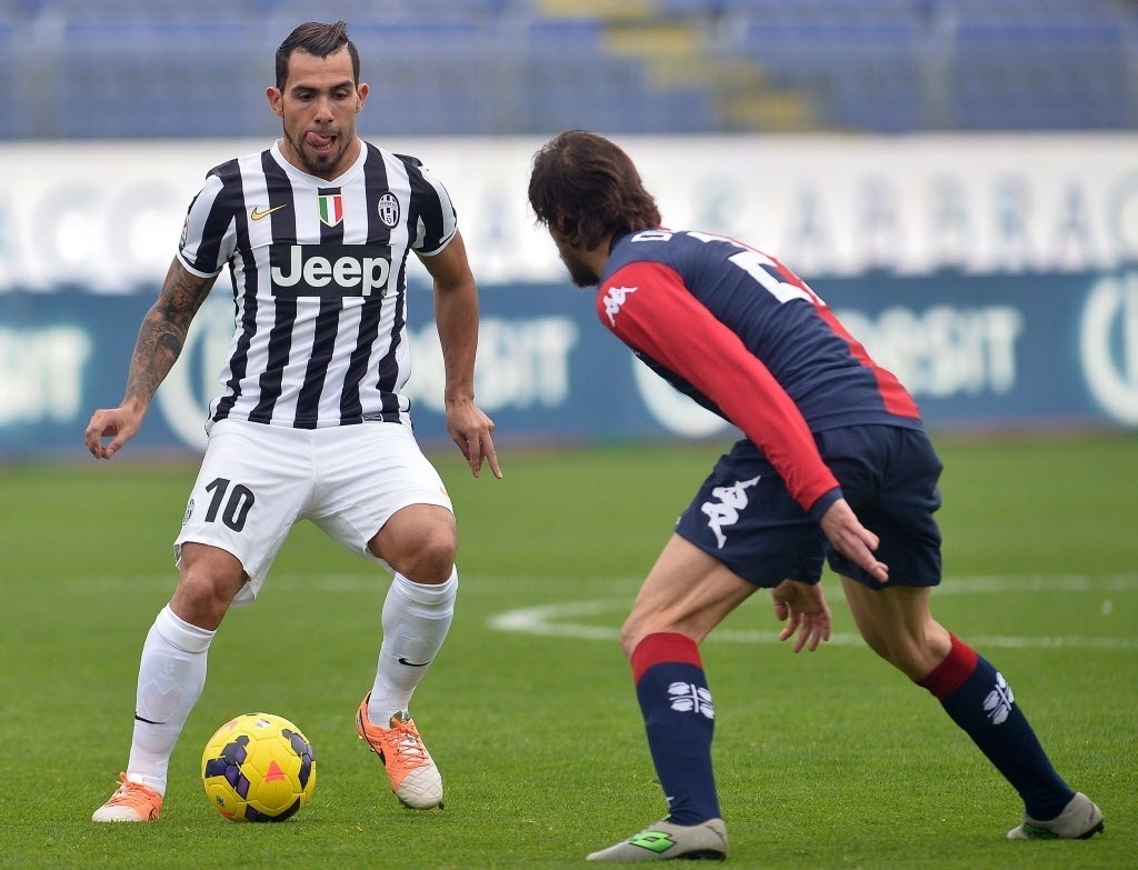 12. jan. 2014 - Tevez e Daniele Dessena disputam jogada durante partida entre Juventus e Cagliari, pelo Campeonato Italiano - AFP PHOTO / GABRIEL BOUYS