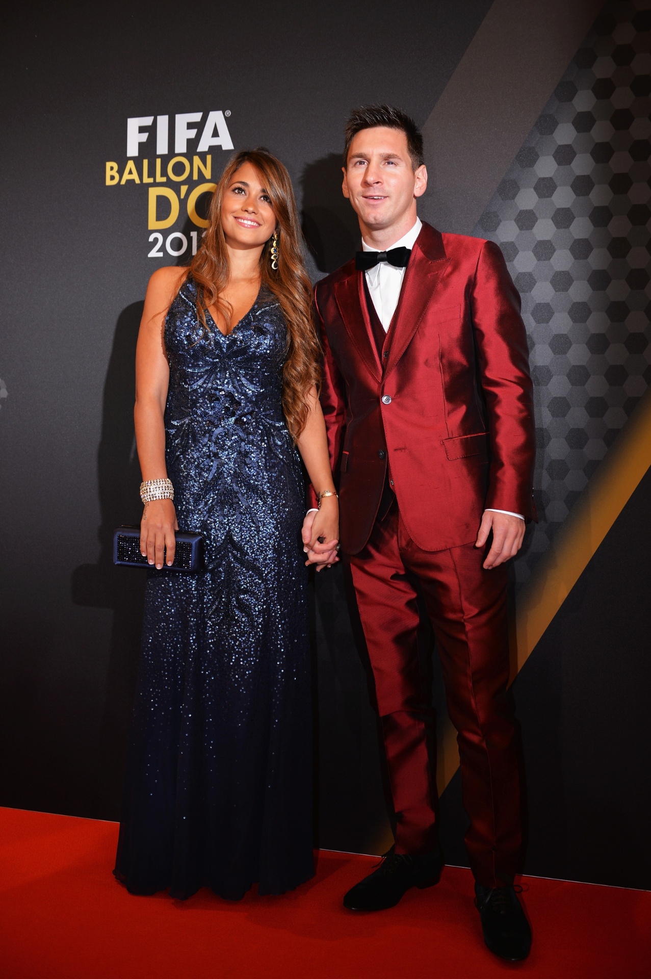 13.jan.2014 - Vestido com um terno vermelho, atacante argentino Lionel Messi posa com a mulher Antonella Roccuzzo - Stuart Franklin/FIFA