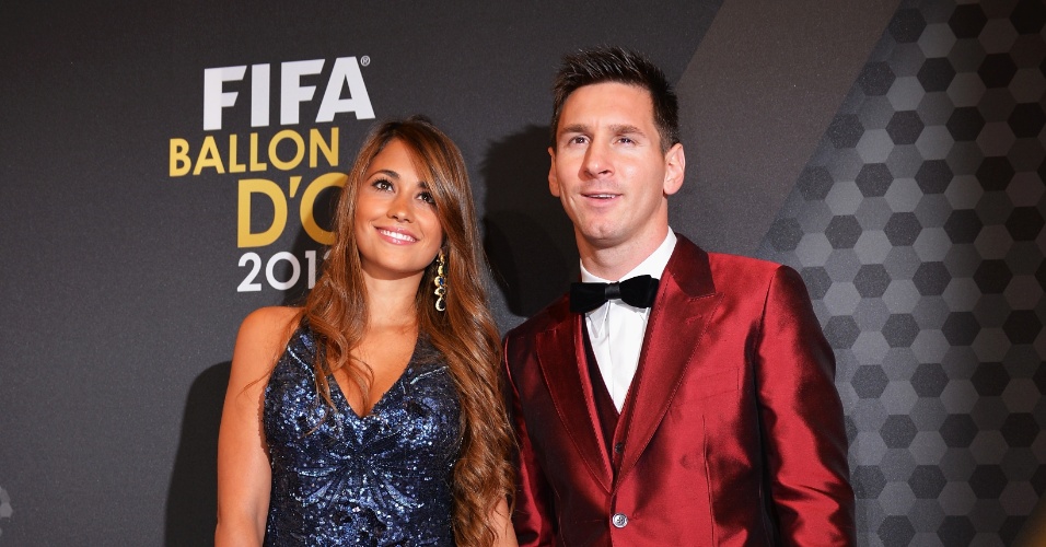 13.jan.2014 - Vestido com um terno vermelho, atacante argentino Lionel Messi posa com a mulher Antonella Roccuzzo
