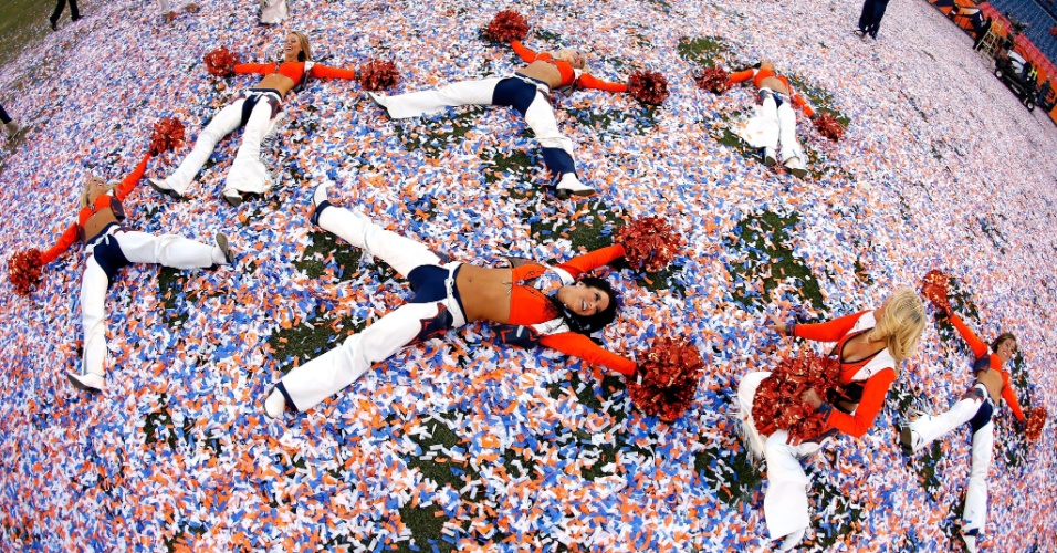19.jan.2014 - Cheerleaders do Denver Broncos brincam no gramado repleto de papéis picados após título da conferência americana