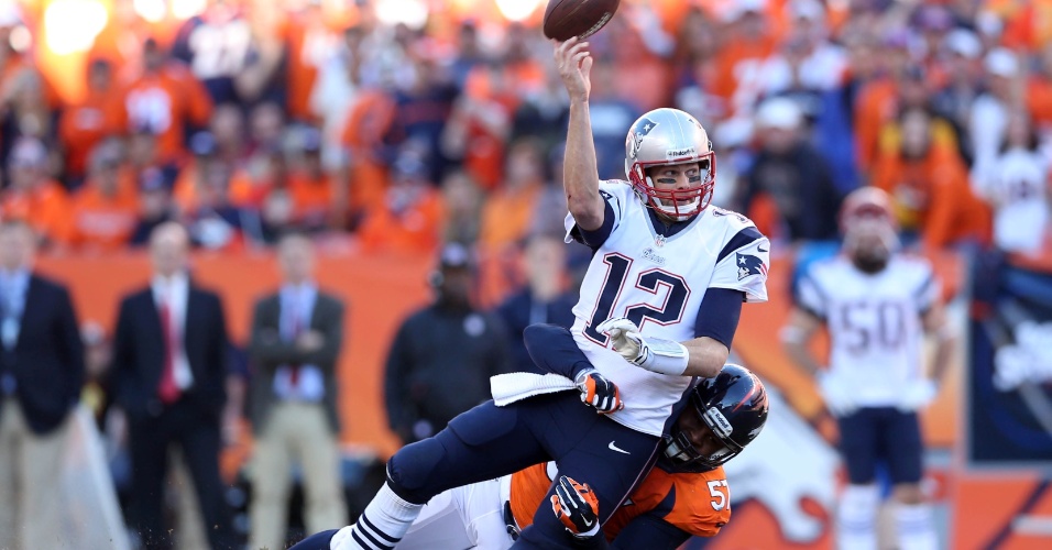 19.jan.2014 - Tom Brady, dos Patriots, é seguro por Jeremy Mincey, dos Broncos, em final da conferência americana da NFL