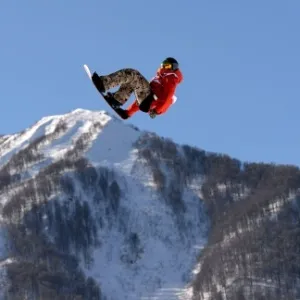 06.fev.2014 - Com montanhas ao fundo, o belga Seppe Smits salta durante sua apresentação no snowboard slopestyle em Sochi - Xinhua/Li Gang