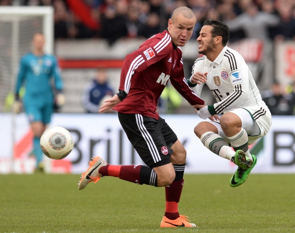 08.fev.2014 - Thiago Alcantara, do Bayern de Munique, leva a pior após dividida de bola com Adam Hlousek, do Nuremberg, pelo Campeonato Alemão. O Bayern venceu por 2 a 0 - CHRISTOF STACHE/AFP