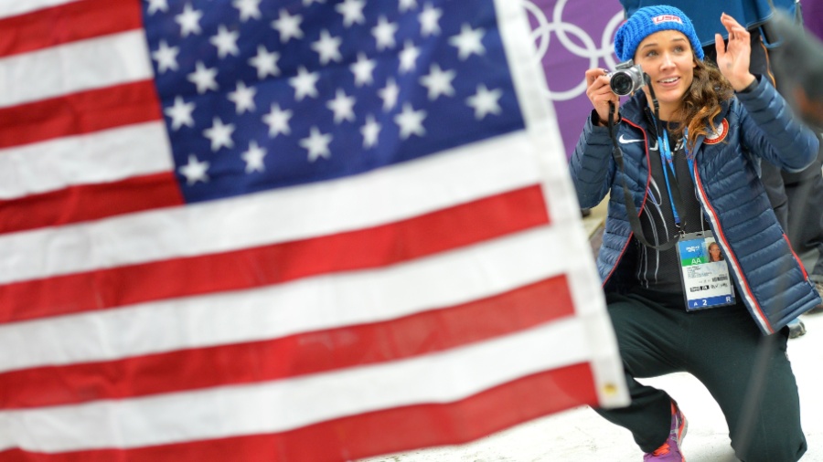 19.fev.2014 - Norte-americana Lolo Jones tira fotos das compatriotas no pódio do bobsled de duplas feminino - AFP PHOTO / LEON NEAL
