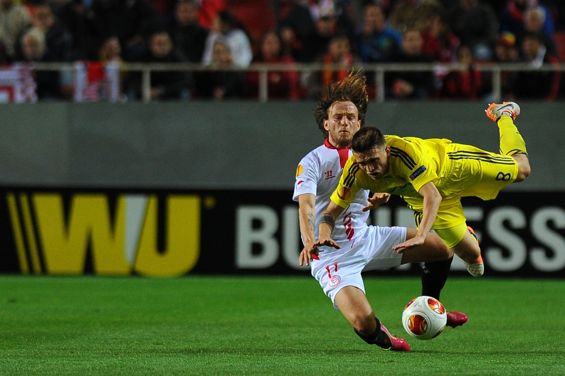 27.02.14 - Ivan Rakitic, do Sevilla, derruba Dejan Mezga, do Maribor; time espanhol venceu por 2 a 1 e garantiu uma vaga para as oitavas da Liga Europa - AFP PHOTO/ JORGE GUERRERO