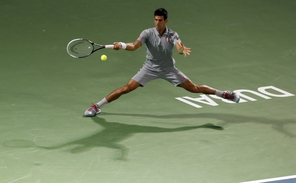 28.fev.2014 - Novak Djokovic estica as pernas para chegar na bola durante a semifinal do Torneio de Dubai contra Roger Federer - AFP PHOTO/KARIM SAHIB