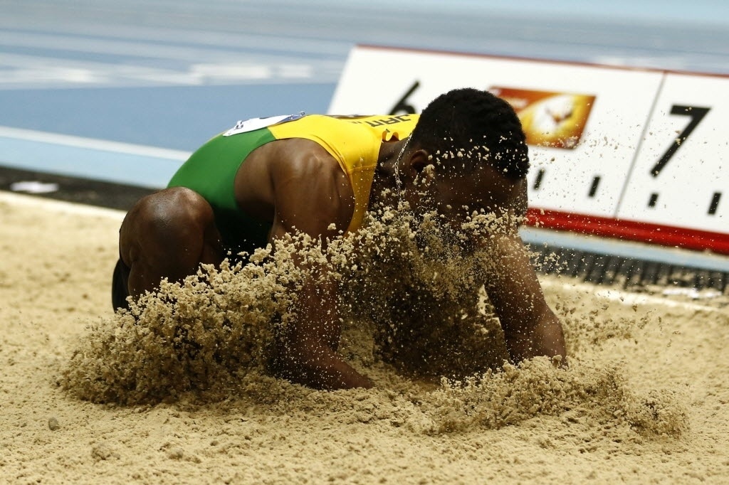 07.mar.2014 - Jamaicano Damar Forbes "come grama" depois de competir no salto em distância no Mundial Indoor de Atletismo, em Sopot, na Polônia - ADRIAN DENNIS/AFP