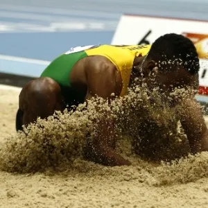 07.mar.2014 - Jamaicano Damar Forbes "come grama" depois de competir no salto em distância no Mundial Indoor de Atletismo, em Sopot, na Polônia - ADRIAN DENNIS/AFP