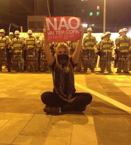13.mar.2014 - Garota, com faixa na boca, levanta cartaz com os dizerem "não vai ter Copa" em São Paulo