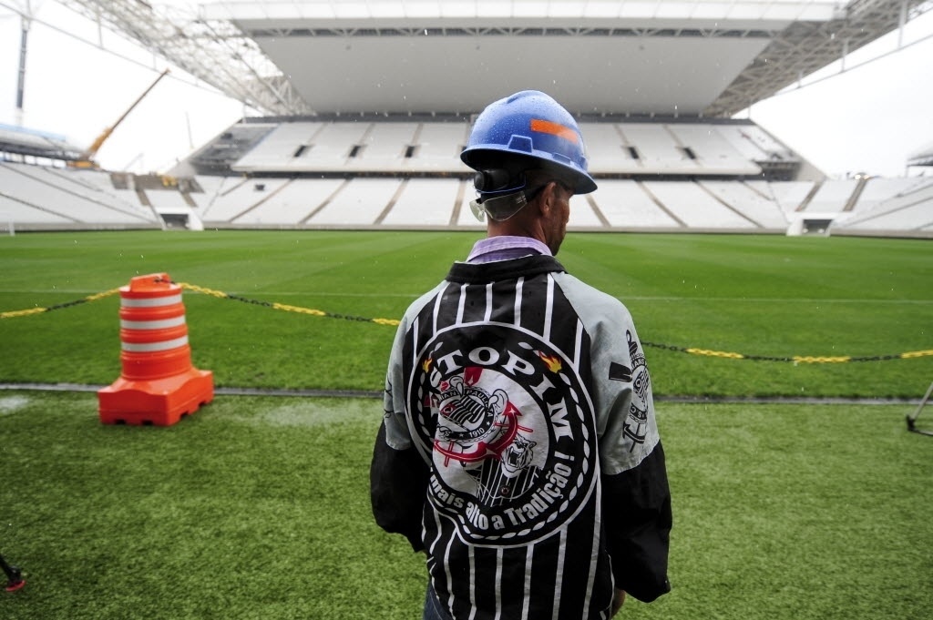 15.abr.2014 - Corintiano, operário do Itaquerão observa gramado do estádio que foi entregue ao clube paulista nesta terça-feira (15/04)