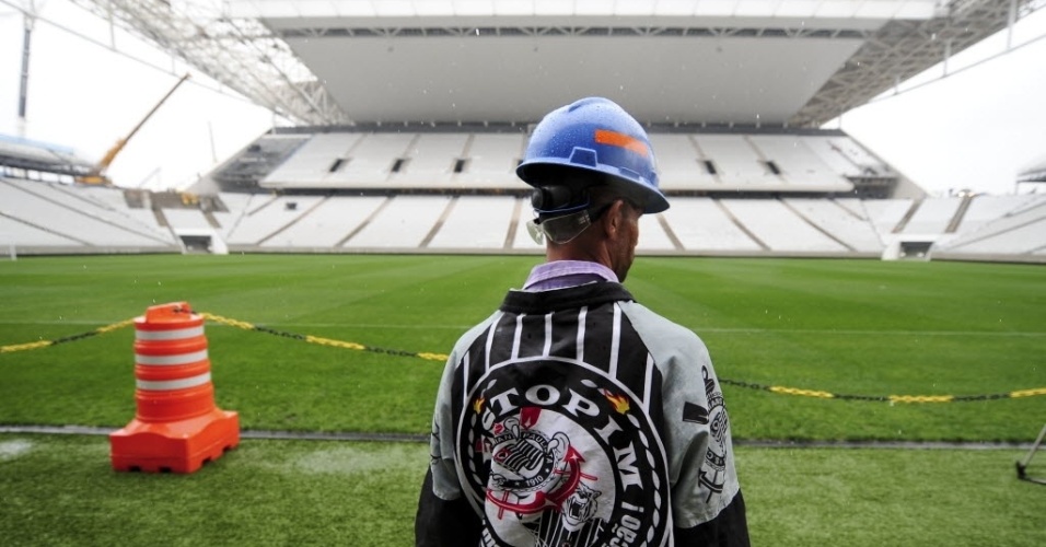 15.abr.2014 - Corintiano, operário do Itaquerão observa gramado do estádio que foi entregue ao clube paulista nesta terça-feira (15/04)