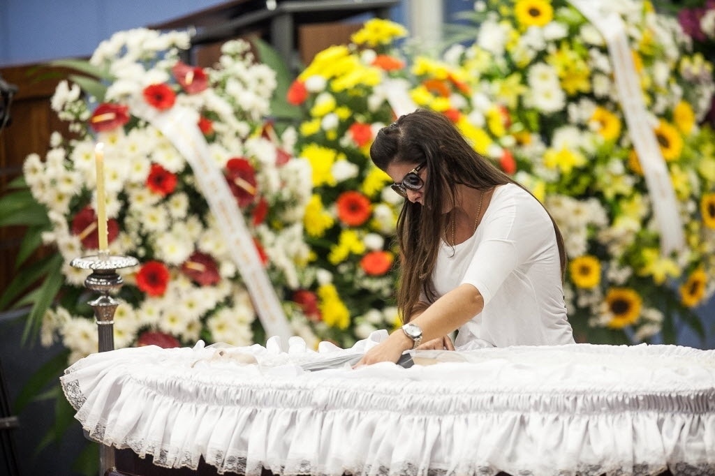 20.abr.2014 - Flávia, viúva de Luciano do Valle, fica ao lado do caixão e presta as últimas homenagens ao marido - Rodrigo Capote/UOL